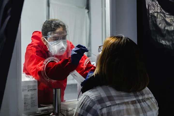 A woman undergoes nasal swabbing for COVID-19 at a booth in the Philippine Red Cross, Mandaluyong.